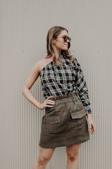 plaid linen one shoulder top on young woman with military green linen mini skirt